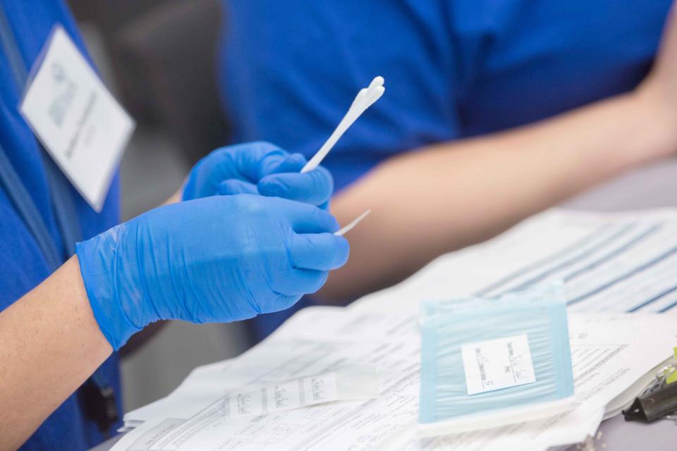 Image of medical professionals holding cotton swab for DNA analysis