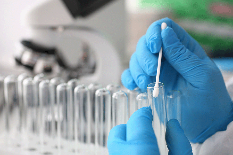 Gloved hands pulling DNA swab from test tube