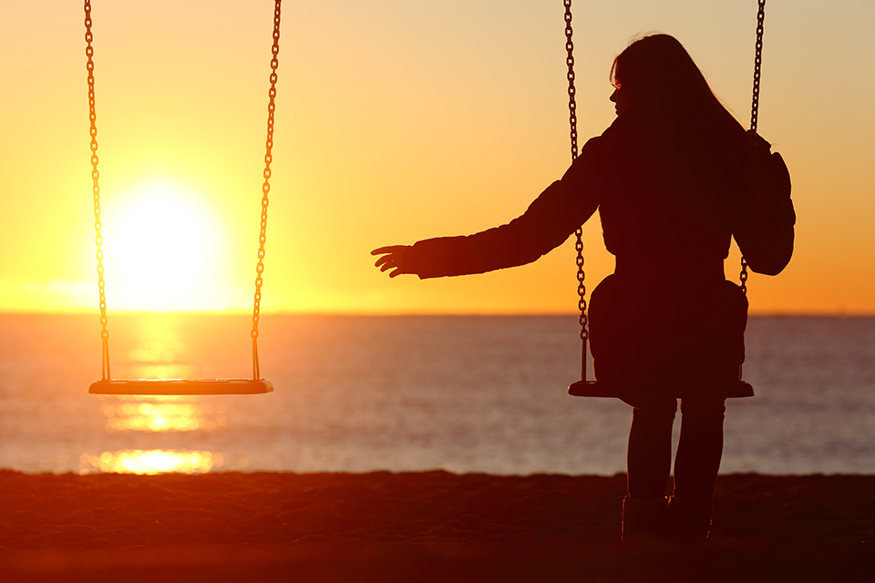 Silhouette of a sad person on a swing